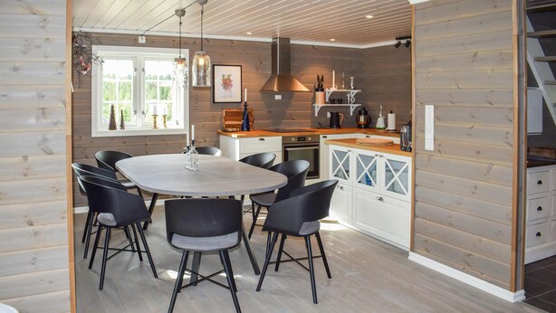 Une cuisine moderne dotée d’un îlot central, de meubles blancs et d’un coin repas avec une table ronde et des chaises.