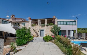 Une villa moderne avec une façade en pierre, une piscine et un espace patio.