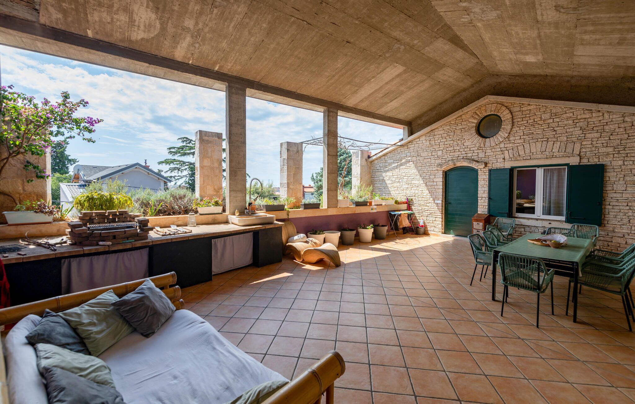 A spacious patio with a stone wall, a dining area, and a seating area with cushions and a sofa.
