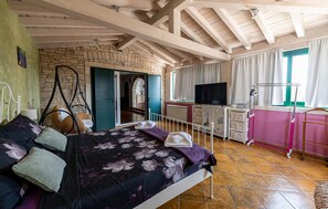 Une chambre à coucher avec un lit, une télévision, une commode et une fenêtre avec des rideaux.