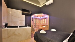 Une chambre d’hôtel moderne avec un sauna en bois, un lit noir et une coiffeuse aux carreaux de marbre.