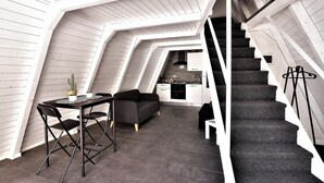 Un appartement de style « loft », moderne et compact, comprenant un coin repas, une cuisine et un escalier.