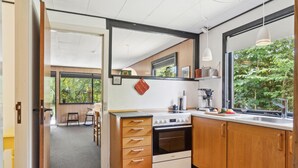 A modern kitchen with wooden cabinets, a built-in oven, and a large window overlooking greenery. - 3 bedroom stunning home in Hasle (Hasle)