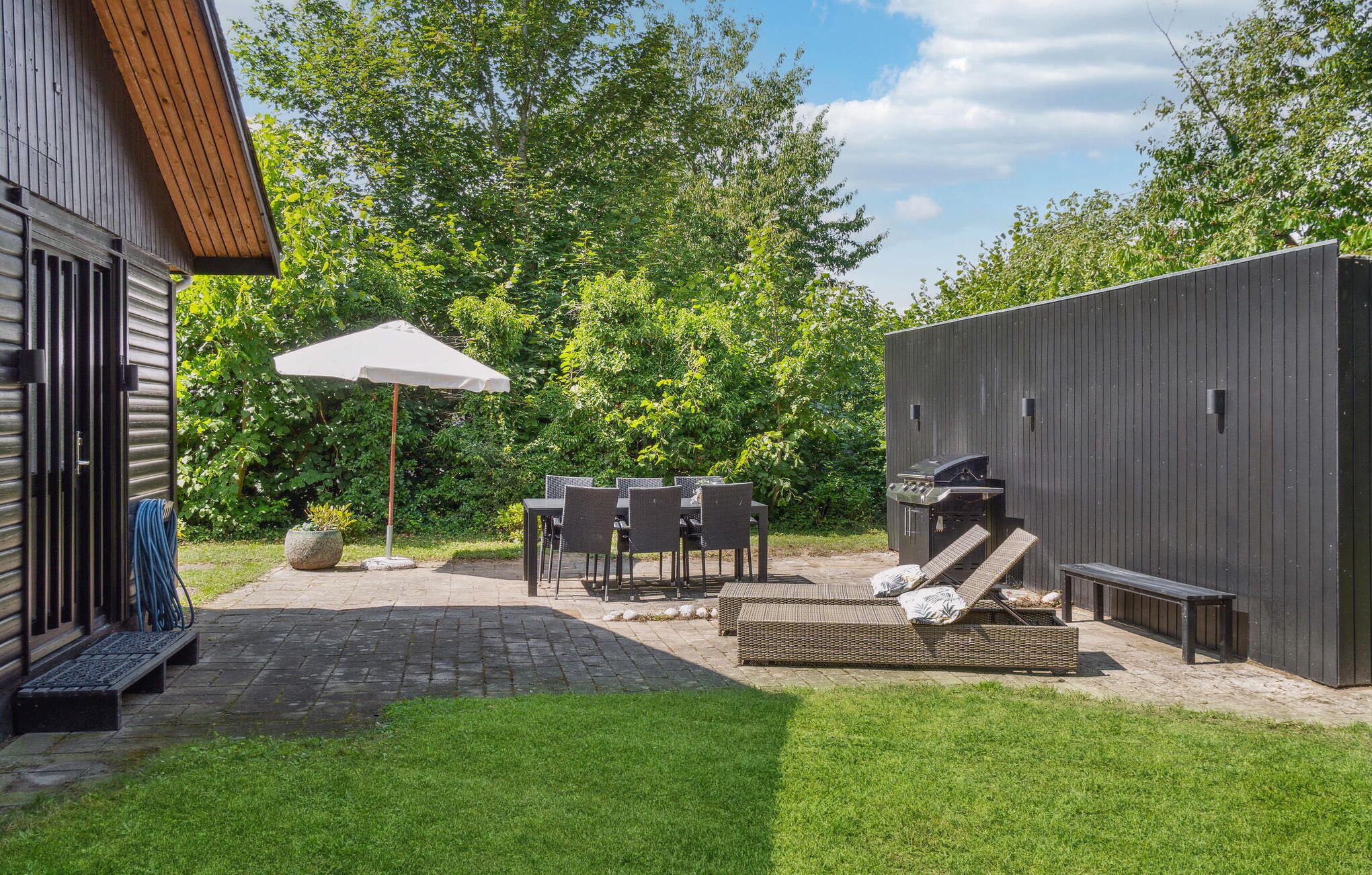 Un espace patio équipé d’un barbecue, de mobilier d’extérieur et d’un parasol.