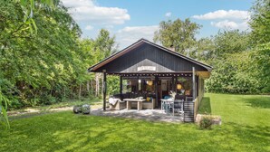 A cozy outdoor seating area with a pergola, a sofa, and a table, surrounded by lush greenery. - 3 bedroom stunning home in Hasle (Hasle)
