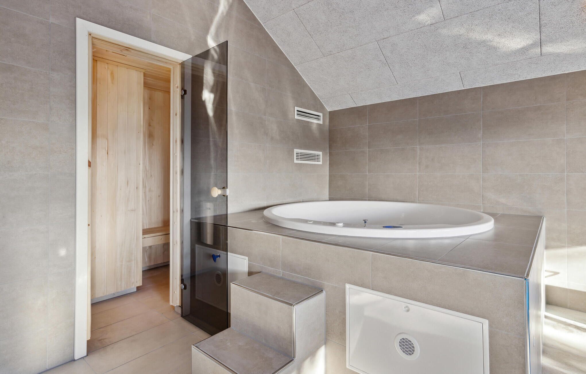 A modern bathroom with a glass shower enclosure, a freestanding bathtub, and a wooden door.