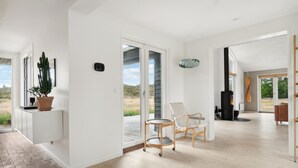 A spacious living area with a large sliding glass door leading to a balcony, a built-in wood-burning stove, and a minimalist design with light-colored flooring and white walls. - Nice home in Fjerritslev with WiFi (Fjerritslev)