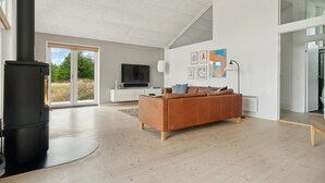 A modern living room with a large window, a fireplace, a sofa, and a flat-screen TV. - Nice home in Fjerritslev with WiFi (Fjerritslev)
