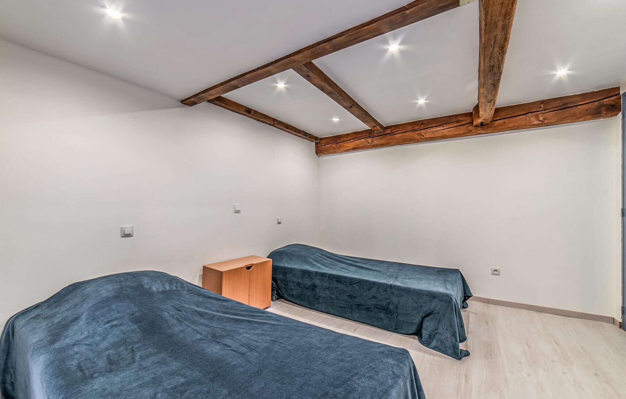 Ein Zimmer mit zwei Betten, Holzbalken an der Decke und einem hellen Boden.