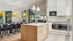 A modern kitchen with white cabinets, a central island with wooden drawers, and stainless steel appliances. - Cozy home in Krakow am See with sauna (Krakow am See)
