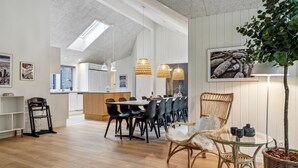 A spacious kitchen with a high ceiling, pendant lighting, and a dining area with wicker chairs and a glass table. - Cozy home in Krakow am See with sauna (Krakow am See)