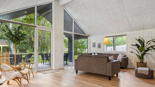 A spacious living area with a large window, a sofa, and a dining table with chairs. - Cozy home in Krakow am See with sauna (Krakow am See)
