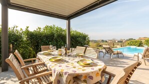 An outdoor dining area with a table set for four, surrounded by wooden chairs, overlooking a swimming pool and a scenic landscape. - Lovely home in Castiglione Del Lago (Castiglione Del Lago)