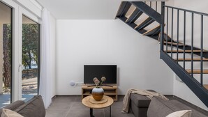 Un salon moderne avec un canapé, une table basse, un téléviseur et un escalier.