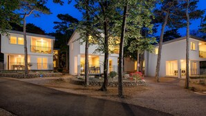 Une maison moderne à deux étages, dotée d’un balcon, d’un chemin en pierre et d ’un petit jardin fleuri.