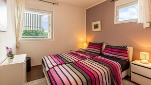 Un dormitorio con cama, mesitas de noche, un escritorio y una ventana con cortinas.