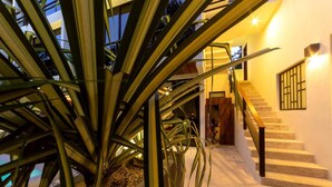 A staircase with a wooden handrail and a wall-mounted light fixture. - BT Rooms Tulum (Tulum)