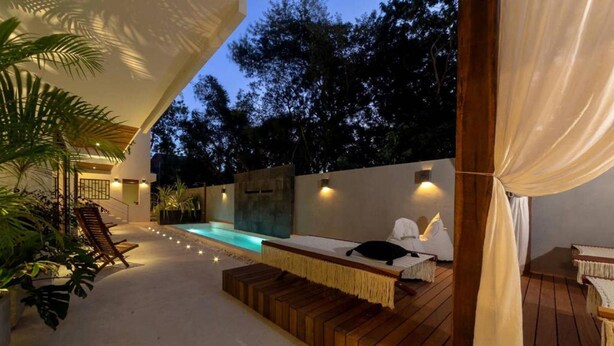 An outdoor pool area with wooden loungers, a small pool, and ambient lighting. - BT Rooms Tulum (Tulum)