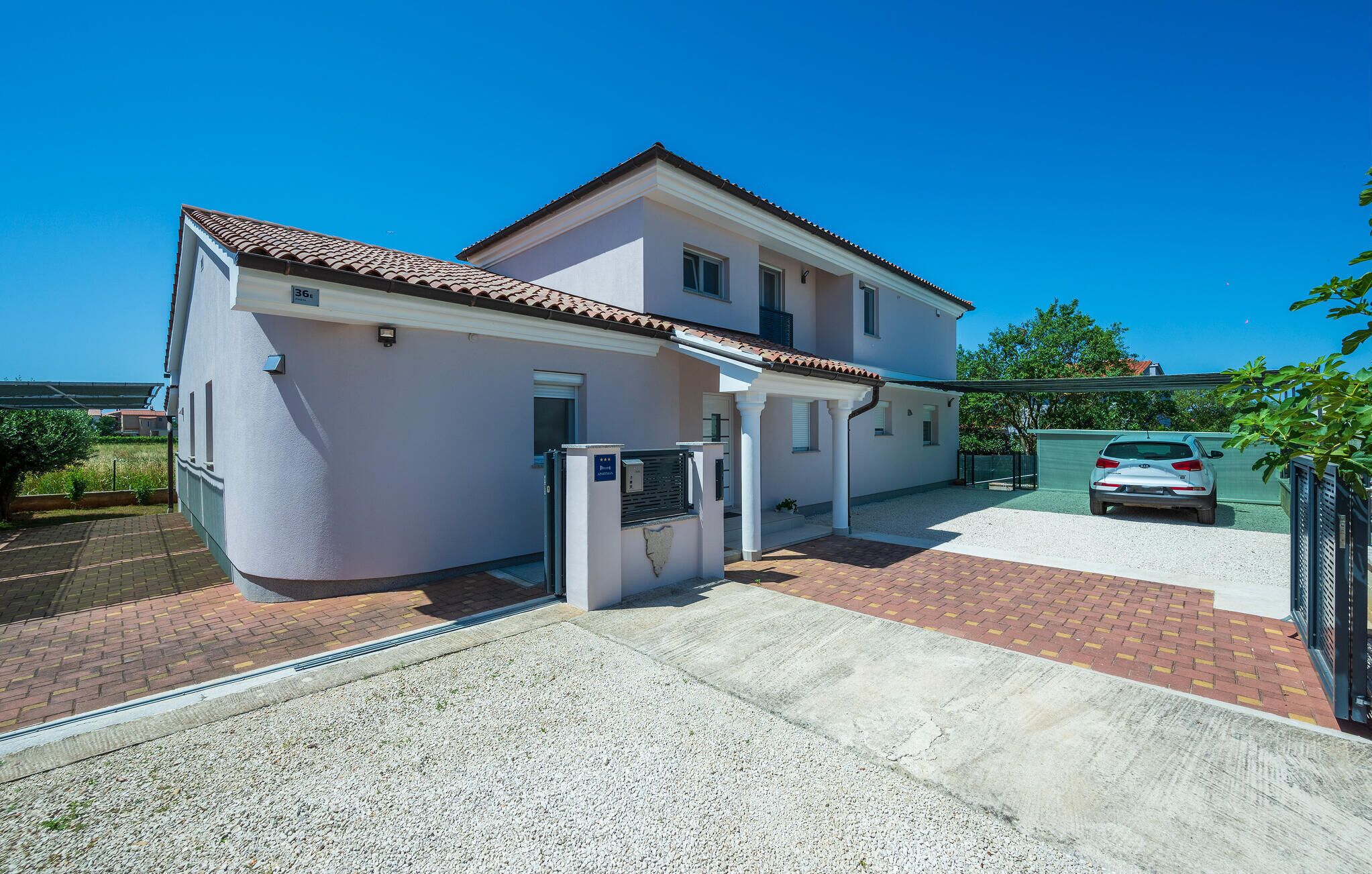 Une maison à deux étages avec un patio couvert et une voiture garée dans l’allée.