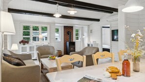 Uma sala de estar aconchegante com lareira, móveis de madeira e um espaço de jantar com mesa posta para dois.