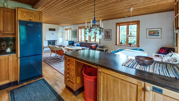 Un'ampia cucina con mobili in legno, un'isola centrale e un'area pranzo con divano e tavolo.