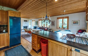 A spacious kitchen with wooden cabinets, a central island, and a dining area with a sofa and table. - Nice home in Båstad with kitchen (Båstad)