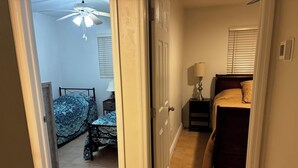 Un dormitorio con dos camas, un ventilador de techo, una mesita de noche y una lámpara.