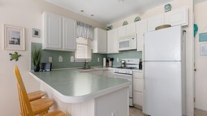 A kitchen with white cabinets, a central island with chairs, a refrigerator, and a microwave. - 4305 Park Road, Sea Isle City (Sea Isle City)