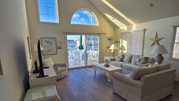 A spacious living room with a high ceiling, large windows, and a ceiling fan. - 4305 Park Road, Sea Isle City (Sea Isle City)