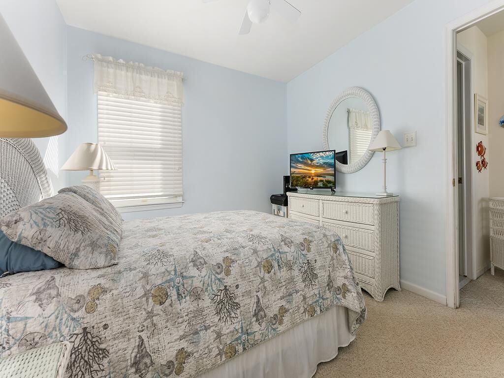 A bedroom with a bed, a dresser, a mirror, and a window with blinds.
