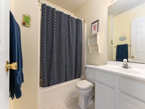 A bathroom with a bathtub, toilet, and a white sink.