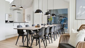 A modern dining area with a long table, black chairs, and pendant lighting. - Beach front home in Krakow am See (Krakow am See)