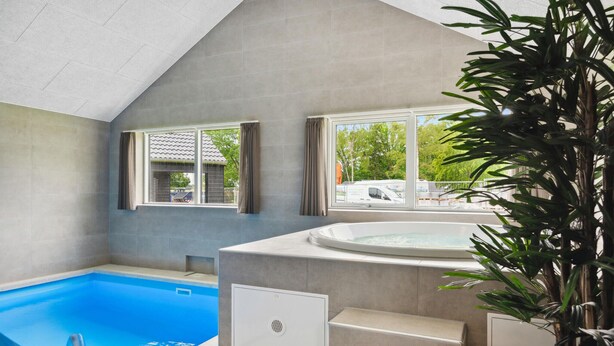 A modern indoor swimming pool with a hot tub, large windows, and a view of the outside. - Beach front home in Krakow am See (Krakow am See)