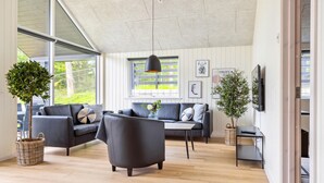 A modern living room with a sofa set, a coffee table, and two potted plants. - Beach front home in Krakow am See (Krakow am See)