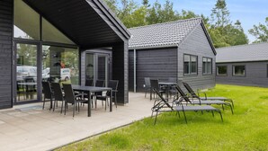 A modern building with a patio area featuring outdoor furniture and a grassy lawn. - Beach front home in Krakow am See (Krakow am See)