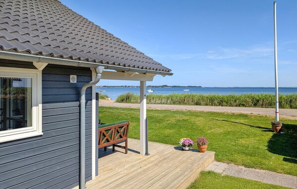 A house with a grey roof, a wooden deck, and a view of the sea.