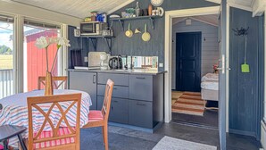 A compact kitchen with a microwave, coffee maker, and various utensils. There is a dining area with a table and chairs, and a small entryway leading to a bedroom. - 1 bedroom awesome home in Blomstermåla (Blomstermåla)