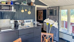 A compact kitchen with a microwave, coffee maker, and a sink. There is a dining area with a table and chairs. - 1 bedroom awesome home in Blomstermåla (Blomstermåla)