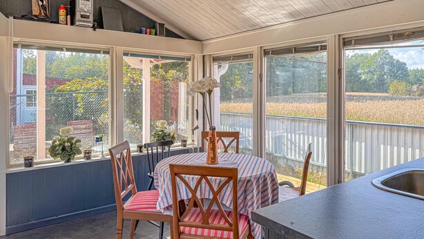 A sunlit kitchen with a dining area, large windows, and a view of a field. - 1 bedroom awesome home in Blomstermåla (Blomstermåla)