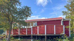 A red wooden building with a red roof, a covered porch, and a fenced area. - 1 bedroom awesome home in Blomstermåla (Blomstermåla)