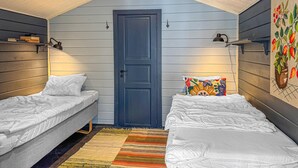 A cozy attic bedroom with two single beds, a wooden door, and a colorful wall hanging. - 1 bedroom awesome home in Blomstermåla (Blomstermåla)