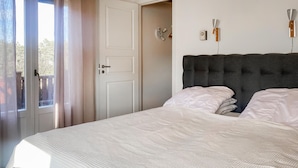 Um quarto com uma cama, uma porta e uma janela.