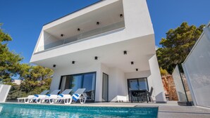 A modern two-story house with a swimming pool, lounge chairs, and a dining area. - Luxurious home in Komarna (Komarna)