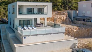 A modern two-story building with a rooftop terrace, outdoor seating, and a view of the surrounding landscape. - Luxurious home in Komarna (Komarna)