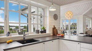 A modern kitchen with large windows, a sink, and a dining area with a table and chairs. - 3 bedroom stunning home in Hejls (Hejls)
