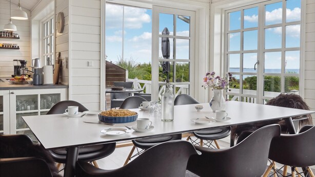 A dining area with a large table, chairs, and a view of the outdoors. - 3 bedroom stunning home in Hejls (Hejls)