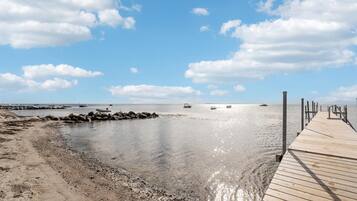 A wooden pier extending into calm waters with boats anchored nearby.