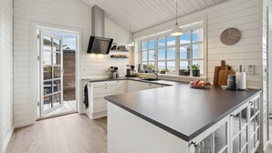 A modern kitchen with white cabinetry, a large island, and a view of the outdoors. - 3 bedroom stunning home in Hejls (Hejls)