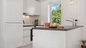 A modern kitchen with white cabinetry, a window with a view of greenery, and a countertop with a bread loaf and a red cup. - Amazing home in Gilleleje with WiFi (Gilleleje)