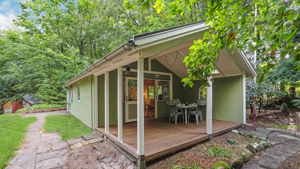 A small, green wooden structure with a porch and a dining area.